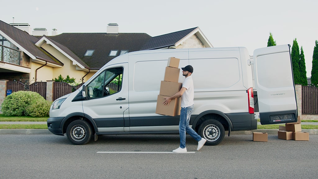 Delivery guy with white truck holding boxes