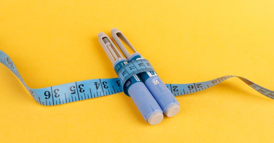 A measuring tape along with two vials of Ozempic.