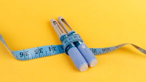 A measuring tape along with two vials of Ozempic.